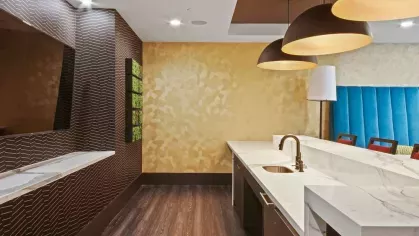 A chic bar area with bold pendant lighting, a long marble counter, and deep red bar stools.
