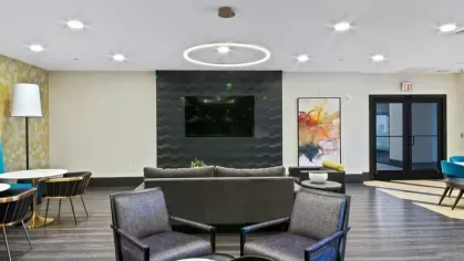 A grand apartment lobby with high ceilings, black and white decor, and elegant seating arrangements.