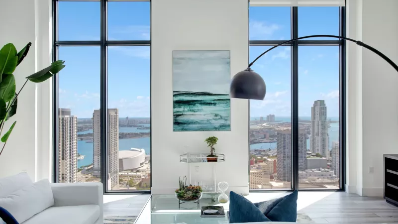A modern living room with floor-to-ceiling windows offering a stunning view of the city and waterfront.