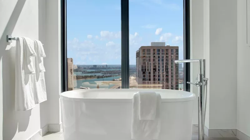 A luxurious bathroom featuring a freestanding soaking tub with a breathtaking skyline and water view.