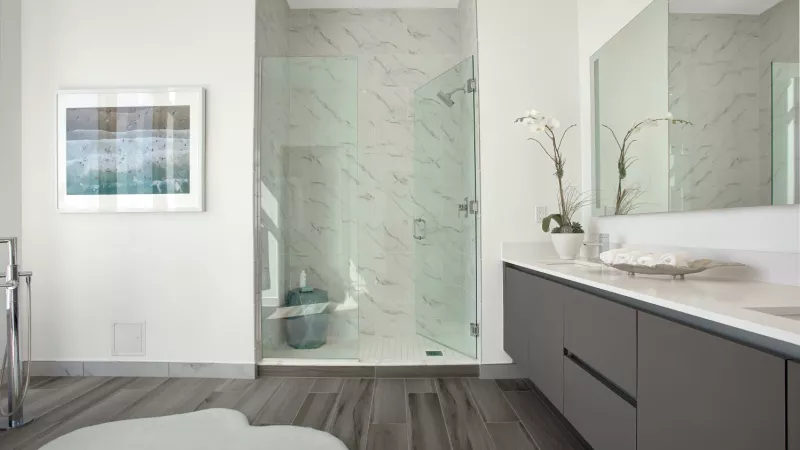 A sleek bathroom with a glass-enclosed shower, dual vanity, and marble accents.