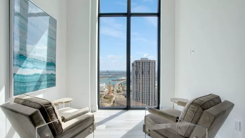 A cozy lounge area with plush chairs facing a window with an incredible city and waterfront view.