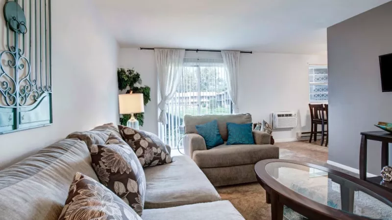 Cozy living room with a plush sectional, decorative pillows, and sliding glass doors leading to a private patio at Silver Lake Manor Apartments.