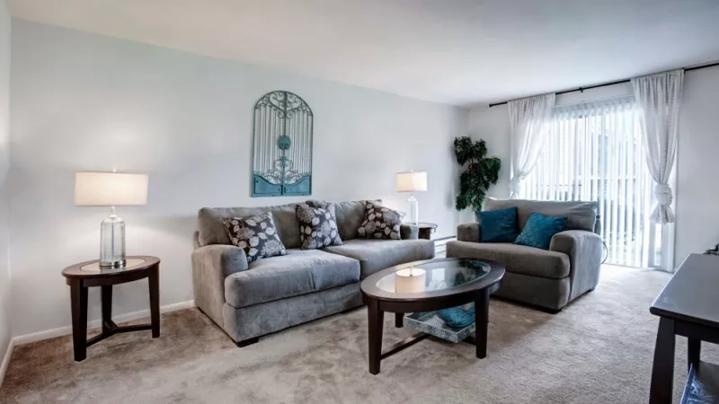 Bright and inviting living space with a stylish sofa set, soft carpeting, and large windows for natural light at Silver Lake Manor Apartments.