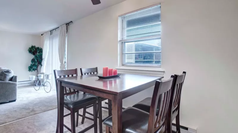 Elegant dining area with a dark wood table, four matching chairs, and a window view at Silver Lake Manor Apartments.