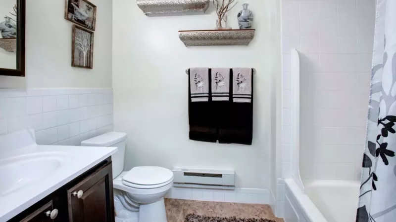 Chic bathroom with a modern vanity, decorative shelves, and a full bathtub and shower combination at Silver Lake Manor Apartments.