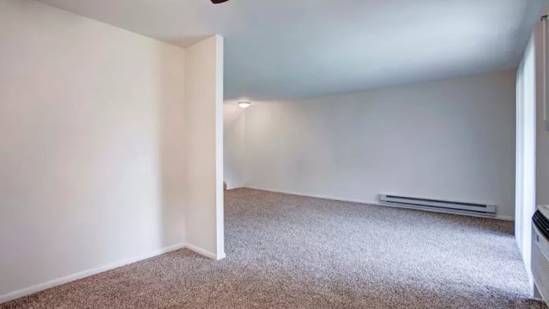 Expansive living area with plush carpeting, neutral walls, and ample natural light from large windows at Silver Lake Manor Apartments.