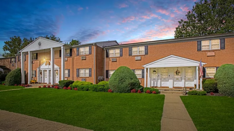 Elegant brick apartment buildings of Silver Lake Manor Apartments captured during sunset, highlighting their colonial-style architecture and vibrant landscaping.