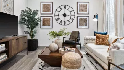 A stylish living room with modern decor, featuring a large wall clock, plush seating, and a cozy ambiance.