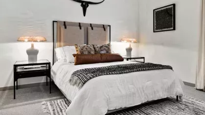 A chic bedroom with a rustic headboard, elegant lighting, and a bold decorative accent above the bed.