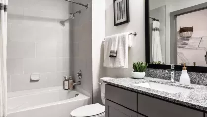 A modern bathroom with a spacious vanity, elegant lighting, and a classic white bathtub.