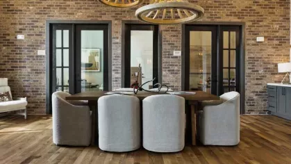 A stylish dining area with a rustic brick accent wall, plush seating, and warm pendant lighting.