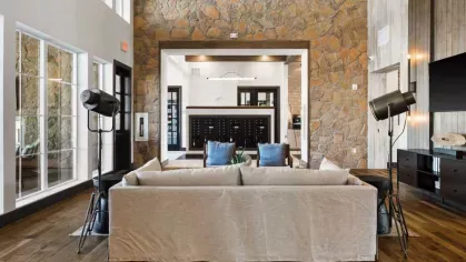  A grand community lounge featuring a high ceiling, stone accent wall, and a luxurious chandelier.