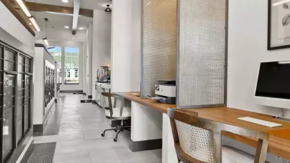 A sleek business center with modern workstations, a long wooden desk, and high-speed internet access.