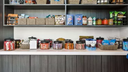 A well-stocked snack bar with a variety of treats, organized baskets, and a contemporary dark wood finish.