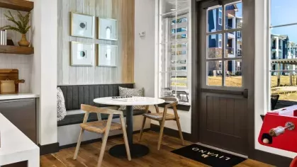 A stylish co-working space featuring a rustic wood wall, modern lighting, and a spacious conference table.