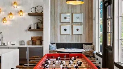  A luxurious lounge with high ceilings, exposed stone walls, and a grand chandelier for an upscale ambiance.