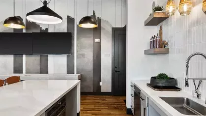 A sleek communal kitchen featuring white quartz countertops, stainless steel appliances, and elegant pendant lighting.