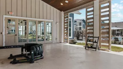 A covered workout space featuring open-air design, resistance training equipment, and a modern aesthetic.