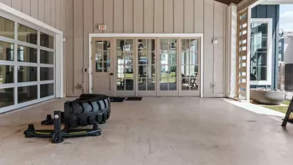 A luxurious pool area with clear blue water, sun loungers, and modern apartment buildings in the background.