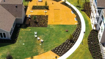 Aerial view of a beautifully landscaped courtyard featuring curved walking paths, green lawns, and designated outdoor seating areas.