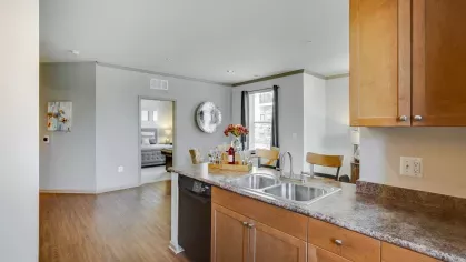 A spacious kitchen seamlessly flows into a dining and living space, with light wood flooring and contemporary finishes enhancing the modern aesthetic.