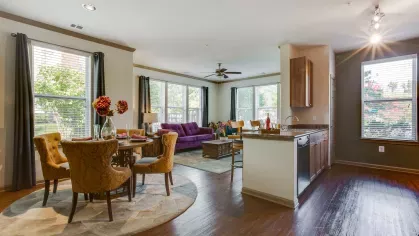 A beautifully designed living and dining area featuring large windows, hardwood flooring, and a cozy seating arrangement. The open layout creates a welcoming environment.