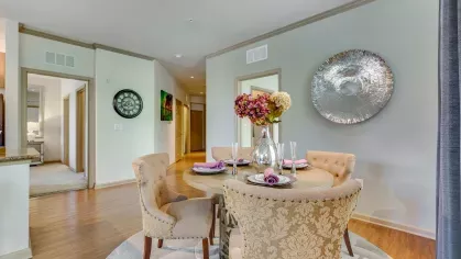 A beautifully arranged dining area featuring a glass dining table, plush chairs, and decorative accents for a sophisticated touch.