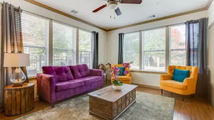 A vibrant living room with large windows, a cozy seating arrangement, and a mix of bold and neutral tones, creating a stylish and comfortable retreat.