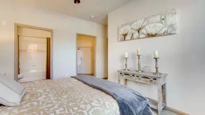 A chic bedroom with a soft color scheme, delicate wall art, and a decorative console with candles, creating a peaceful retreat.