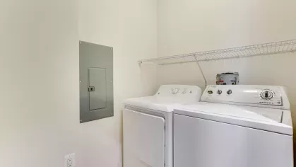 A dedicated laundry space with a full-size washer and dryer, along with built-in shelving for added convenience.