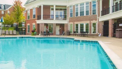A sparkling swimming pool set against the backdrop of an elegant clubhouse, offering a luxurious and relaxing outdoor space.