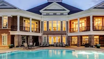 The community pool beautifully illuminated at twilight, with warm lighting from the clubhouse enhancing the serene and inviting atmosphere.