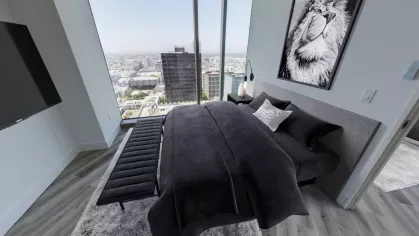 Penthouse bedroom at Nari Koreatown with dark bedding, lion artwork, and floor-to-ceiling windows with downtown skyline views