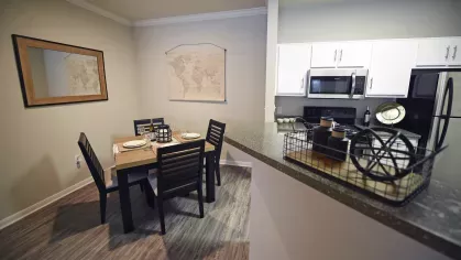 Contemporary dining area with a view into the fully equipped kitchen at Gates at Citiplace apartments