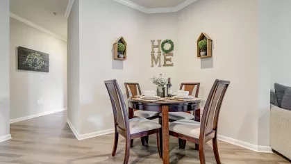 Corner dining space with round table and decorative shelving at Gates at Citiplace apartments