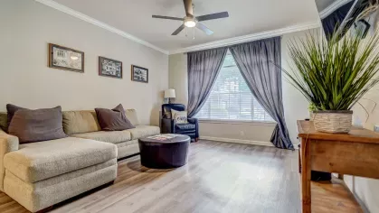 Spacious living room with sectional sofa, natural light, and wood-style floors at Gates at Citiplace in Baton Rouge