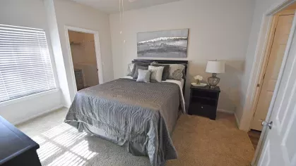 Primary bedroom with walk-in closet and plush carpeting at Gates at Citiplace apartments in Baton Rouge, Louisiana.