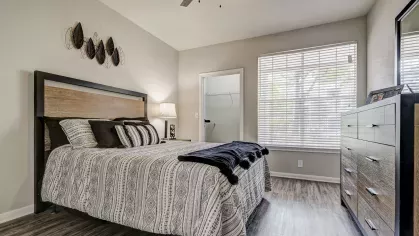 Stylish bedroom with wood-look flooring and walk-in closet at Gates at Citiplace apartments in Baton Rouge.