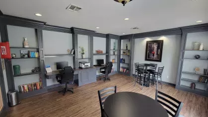 Resident business center with workspaces and bookshelves at Gates at Citiplace luxury apartment community in Baton Rouge.