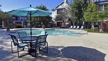Sunny pool area with turquoise lounge chairs and patio seating at Gates at Citiplace in Baton Rouge
