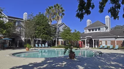 Gated swimming pool surrounded by lush landscaping and lounge seating at Gates at Citiplace apartments