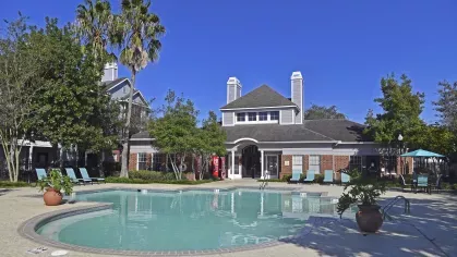 Gates at Citiplace’s resort-style pool with palm trees and red brick clubhouse in Baton Rouge, Louisiana