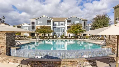 Infinity-edge pool with lounge chairs and a view of the modern apartment buildings at Grandview at Lake Murray
