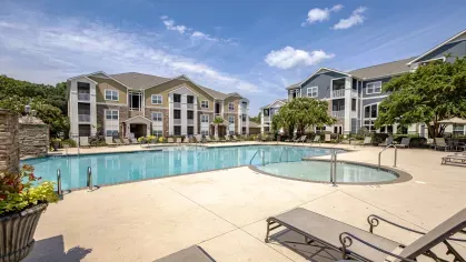 Sunny day at the community pool with sundeck and whirlpool, adjacent to tan and blue apartment buildings