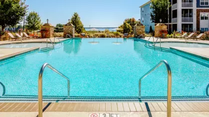 Resort-style pool with ladder entry, stone columns, and lake views in the distance