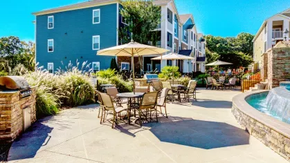 Outdoor dining and grill station beside waterfall pool feature with stone accents