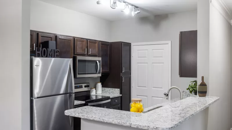 Modern kitchen with stainless steel appliances and granite countertops at Lauren Ridge Apartments.