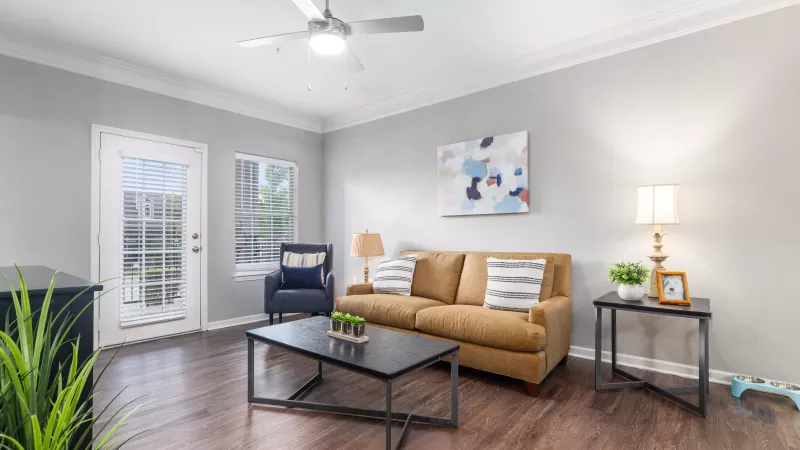 Living room featuring a tan sofa, accent chair, and access to a private patio at Lauren Ridge.