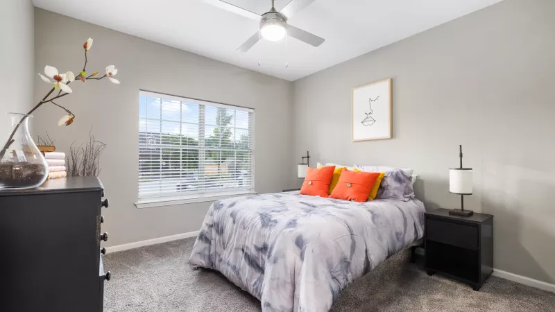 Bedroom with ceiling fan, large window, and contemporary decor in a Lauren Ridge apartment.